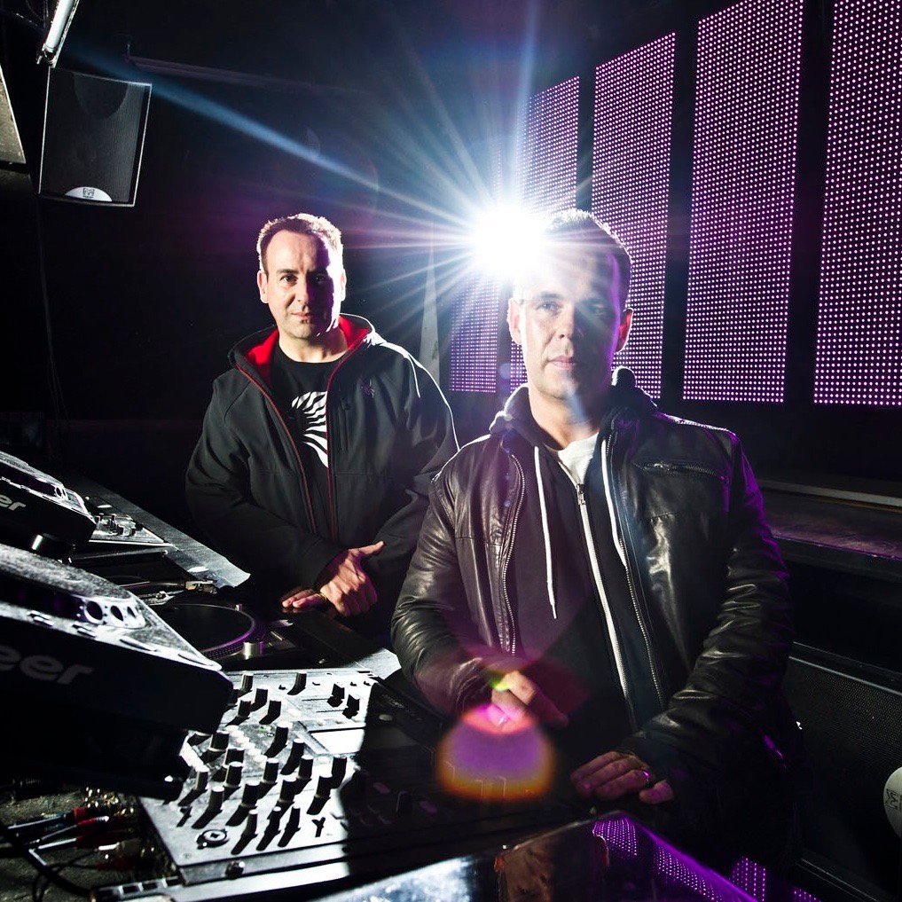 Utah Saints promotional portrait beside DJ equipment