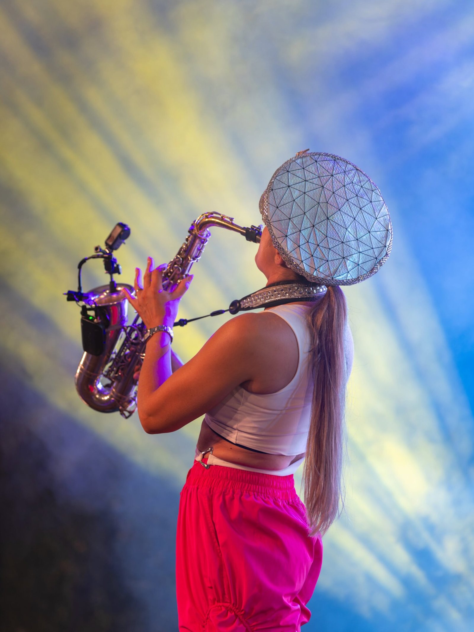 Ellie Sax performing from behind under colourful stage lighting